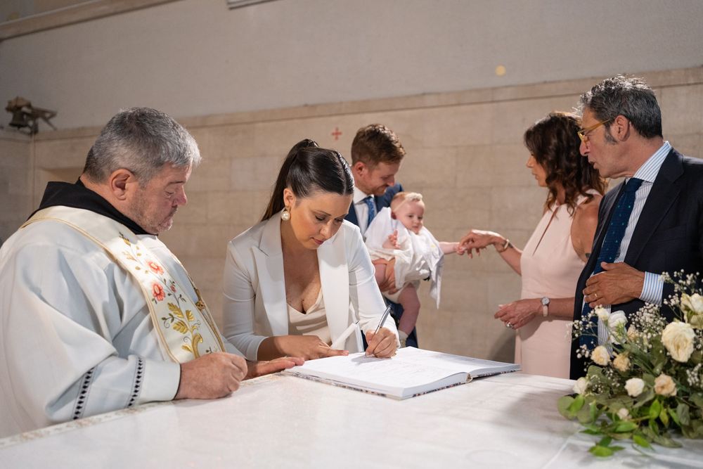 People signing official documents at a formal ceremony with papers spread across a long table.
