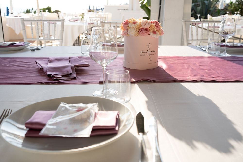 Elegant table settings with pink accents and white plates at an outdoor wedding reception.