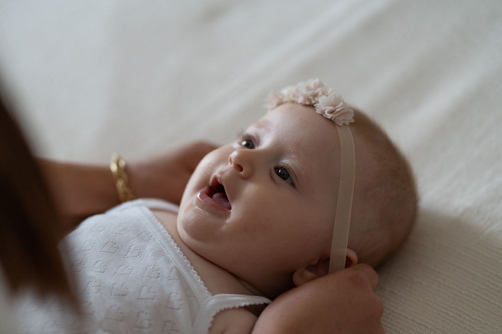 Close-up shots of a baby lying on white bedding showing various expressions and movements.
