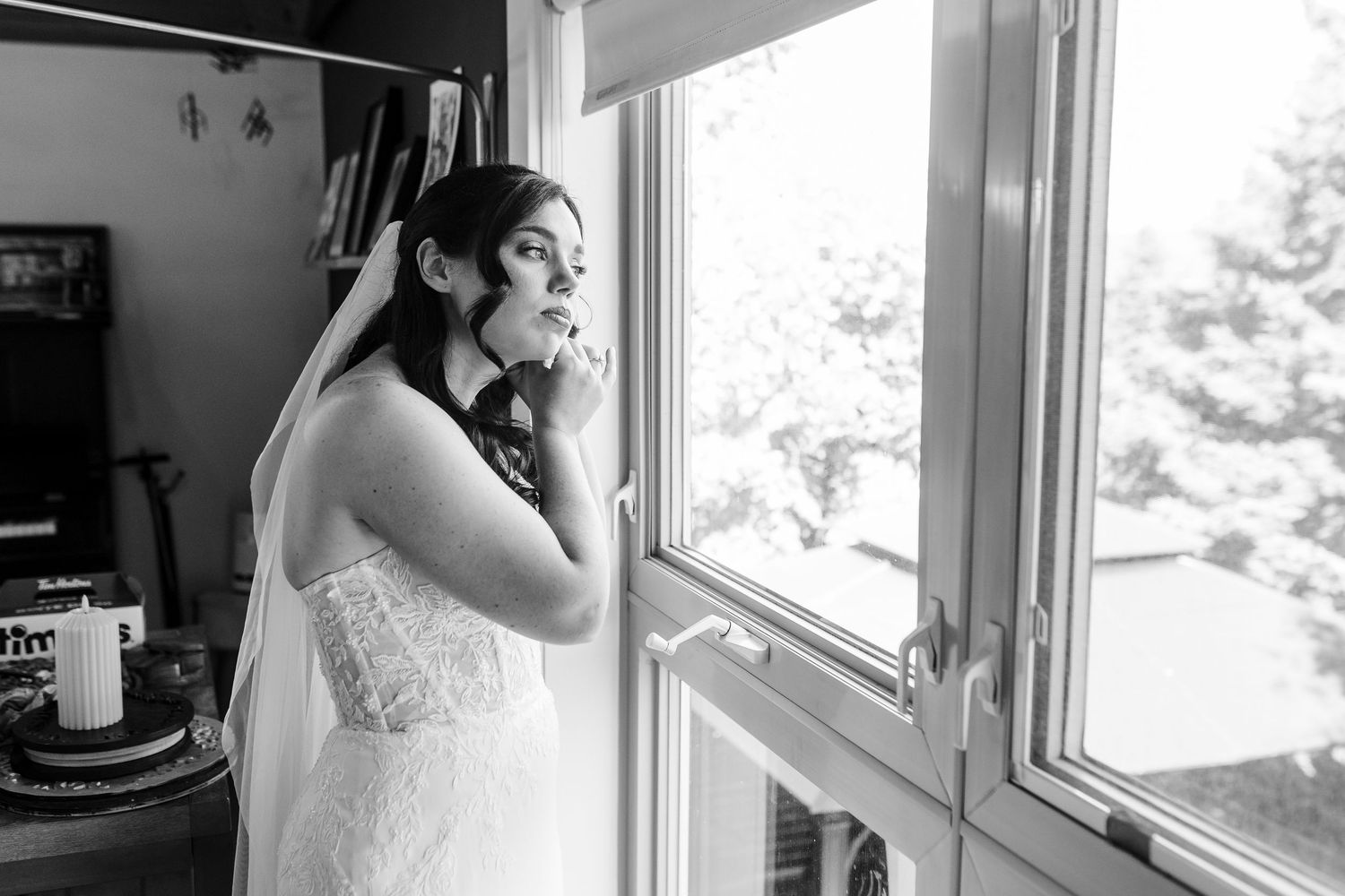 A sequence of black and white wedding preparation photos showing details of a bridal gown by a window.