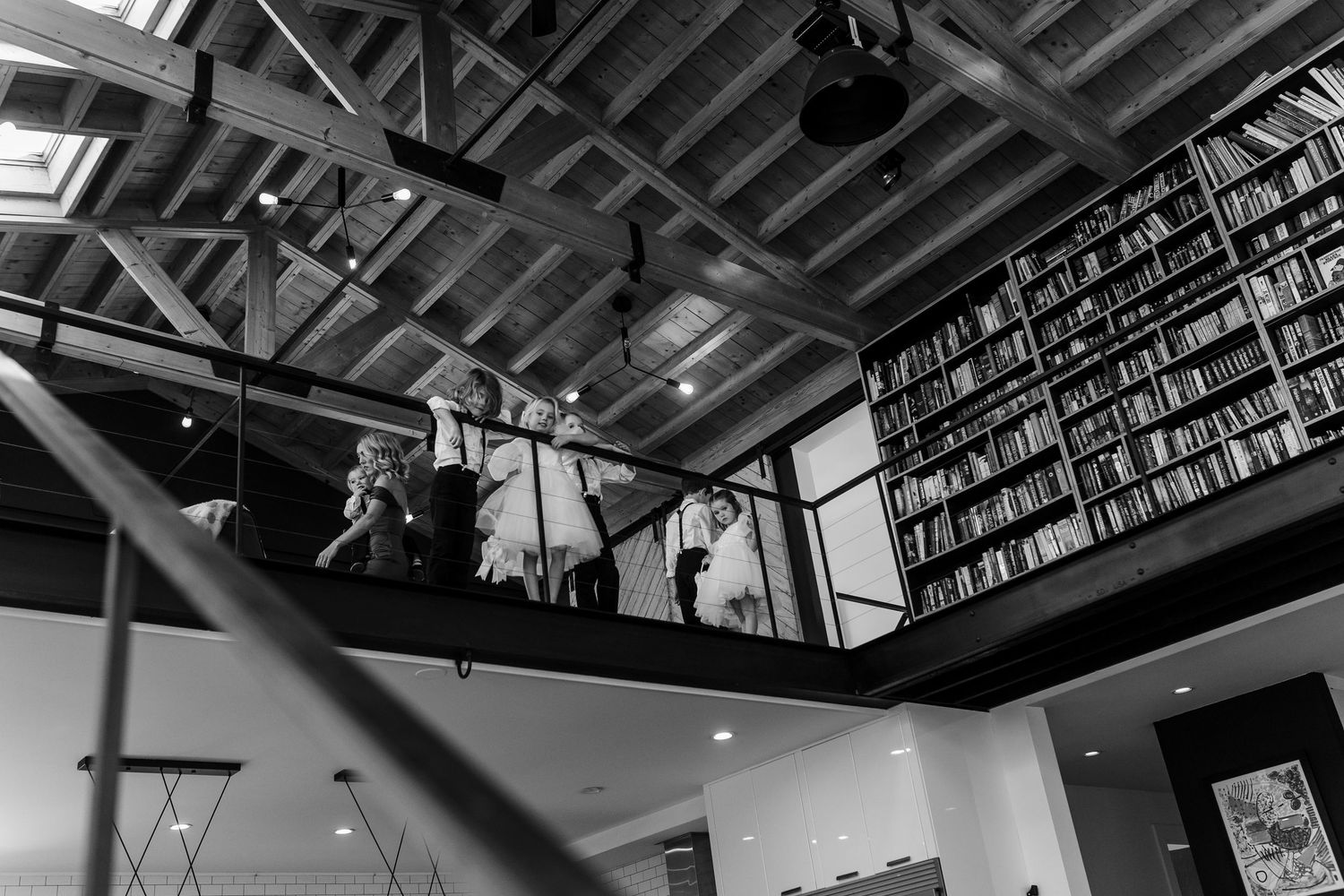 Interior view of a modern library with exposed industrial ceiling and rows of bookshelves along the walls.