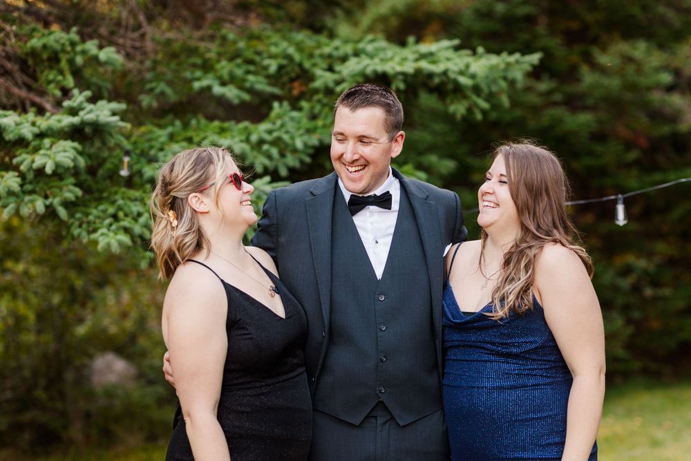 Wedding party members in formal attire share joyful moments together outdoors during a celebration.