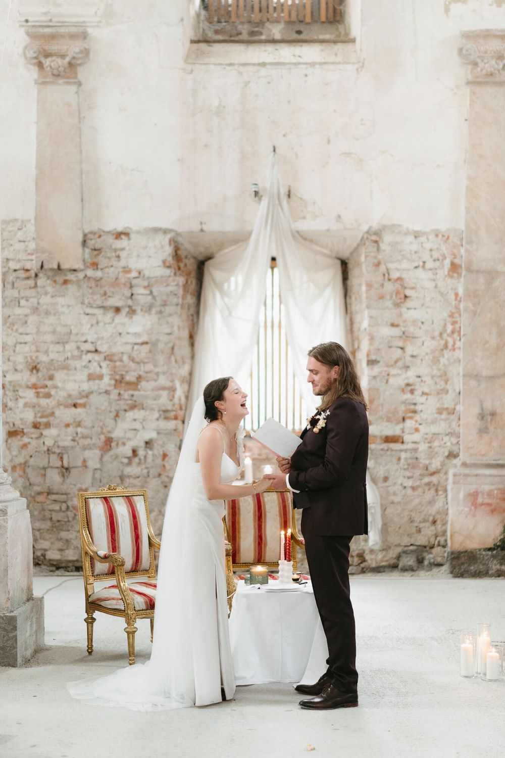 Wedding ceremony in a rustic brick room with vintage chairs and elegant decor.