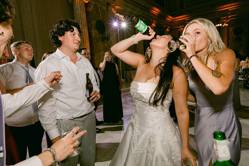 Wedding guests dance and celebrate on a dimly lit dance floor during an evening reception party.