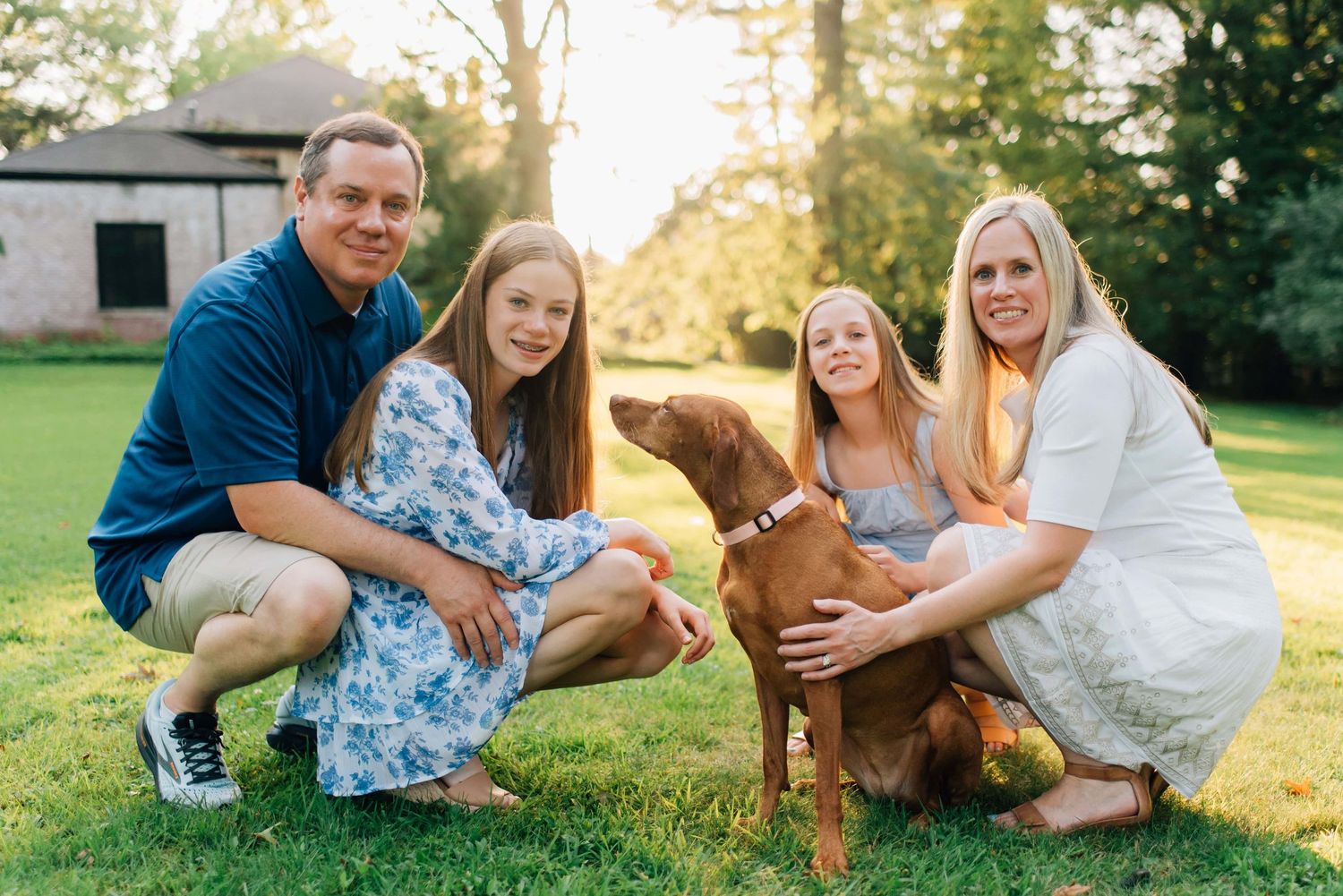 Parents cuddling kids and dog during golden hour