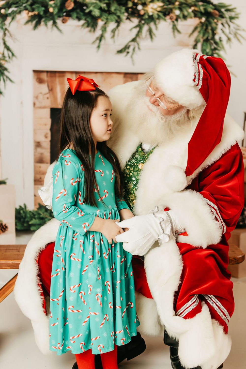 A child in a turquoise dress interacts with Santa Claus in a series of festive holiday photos.
