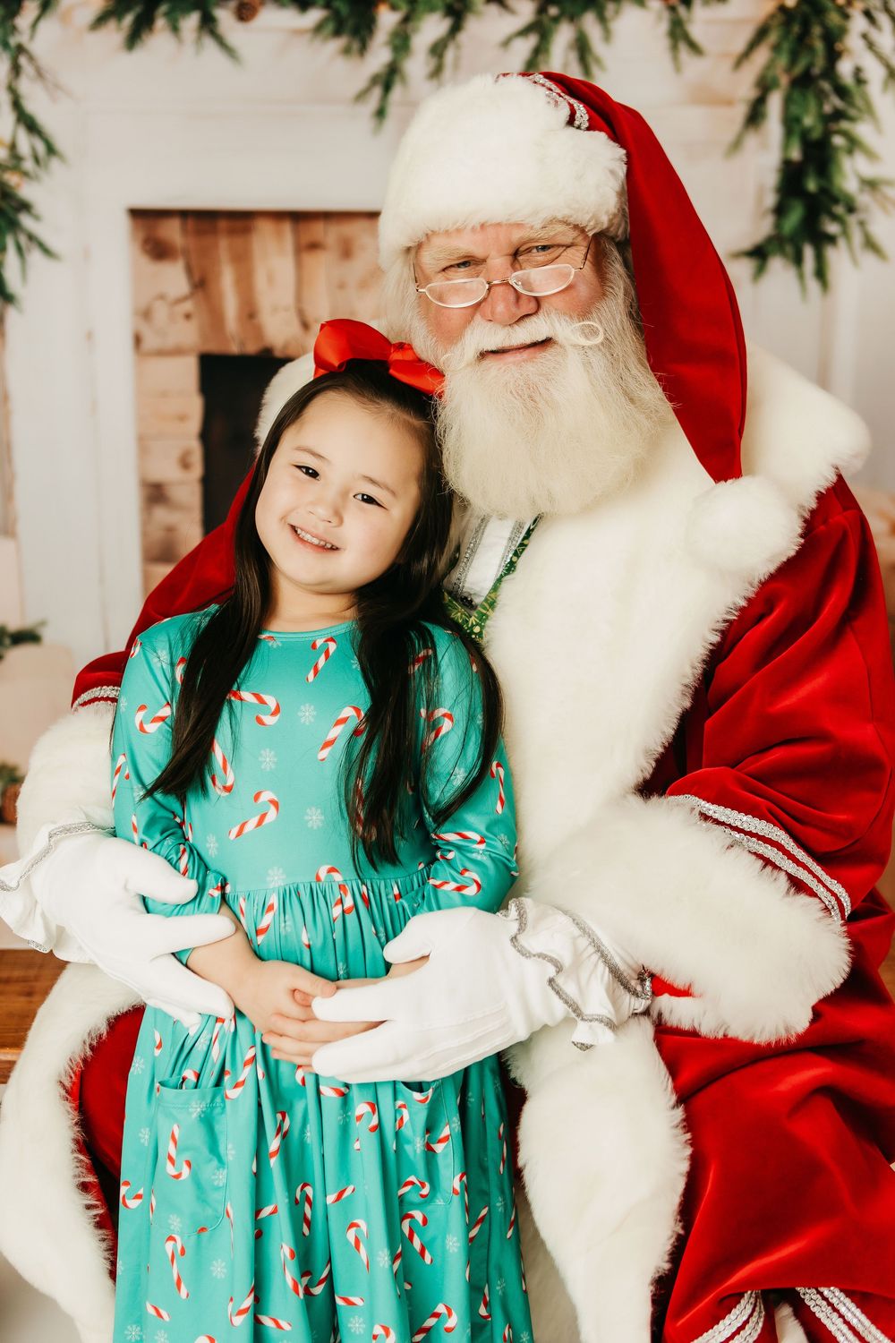 A child in a festive green candy cane dress poses with a traditional holiday figure in red and white.