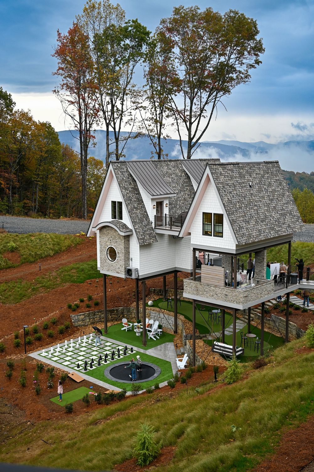 White modern A-frame buildings with geometric architecture set on a hillside with manicured landscaping.