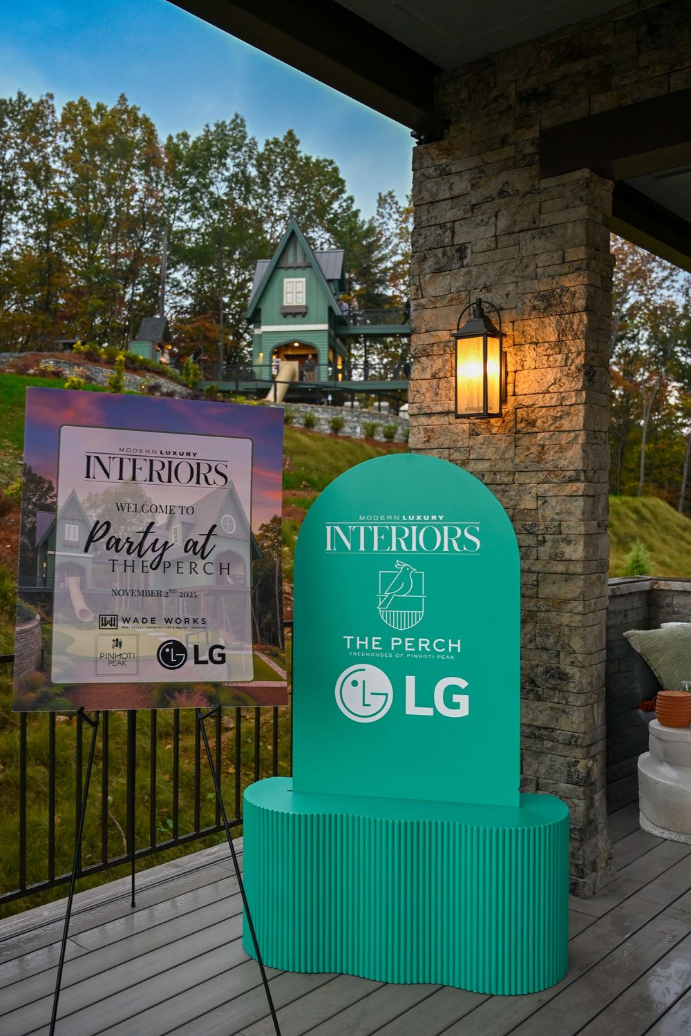 Outdoor display setup with teal-colored bench and promotional banners against stone pillars at dusk.