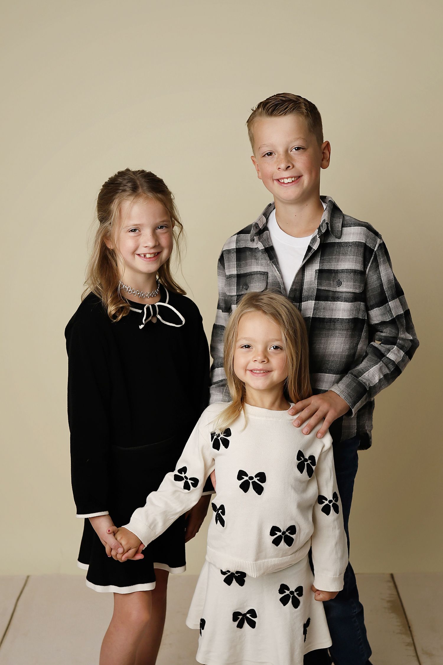 Studio portrait series showing siblings in coordinated black and white outfits against a neutral backdrop.