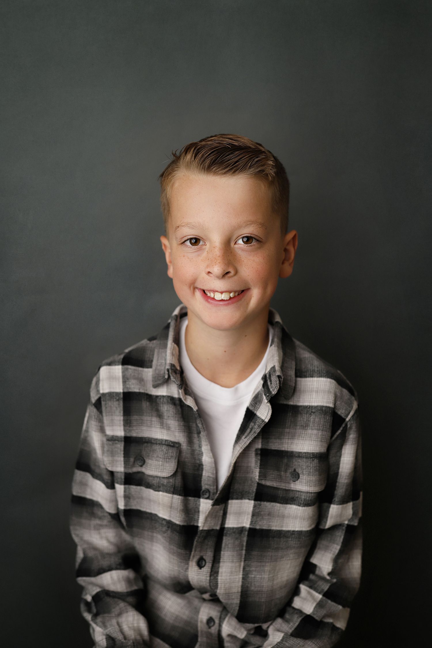 A series of three portrait photographs showing a young child in a plaid flannel shirt against a dark gray background.