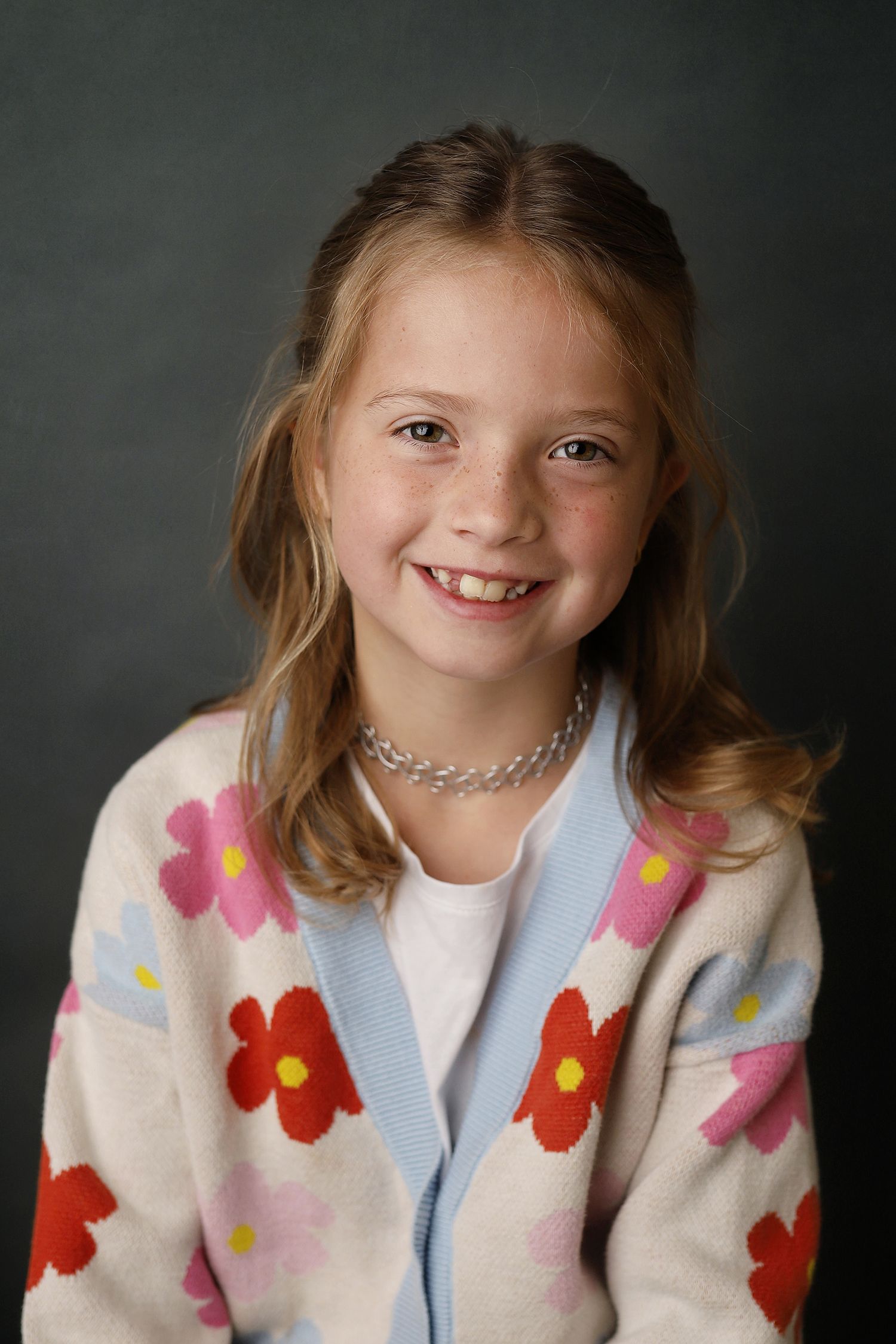 A series of portrait photos showing a child in a floral print jacket against a dark gray background.