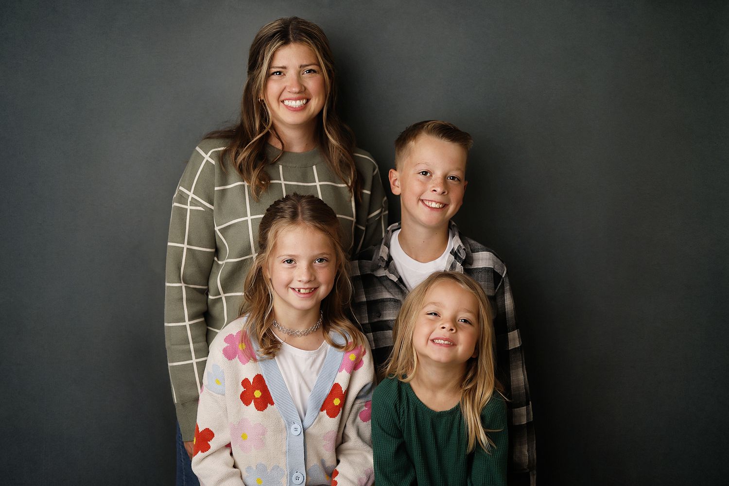 A family wearing coordinated gray and white outfits poses together for a series of professional portraits.