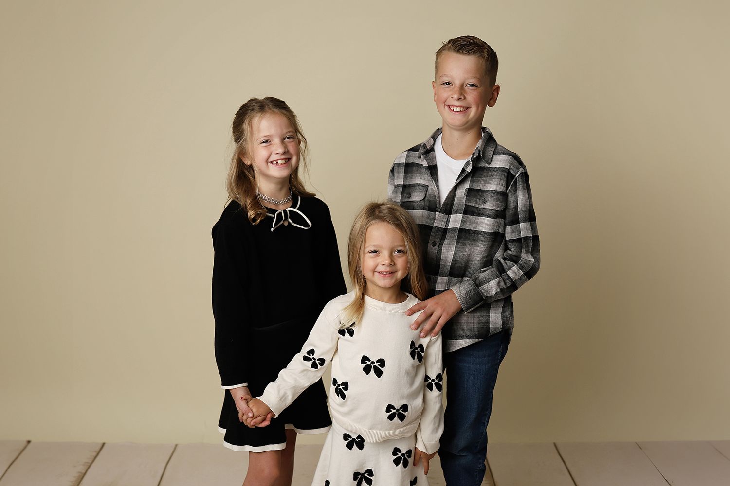Children pose together in coordinating black and white outfits for a family portrait session.