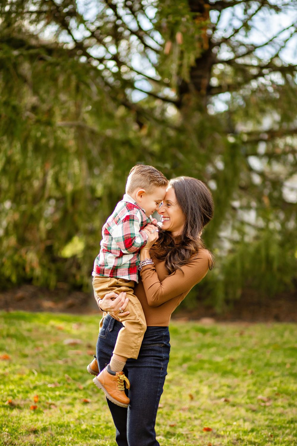 A mother and child share tender moments in a series of playful outdoor portraits in a wooded setting.