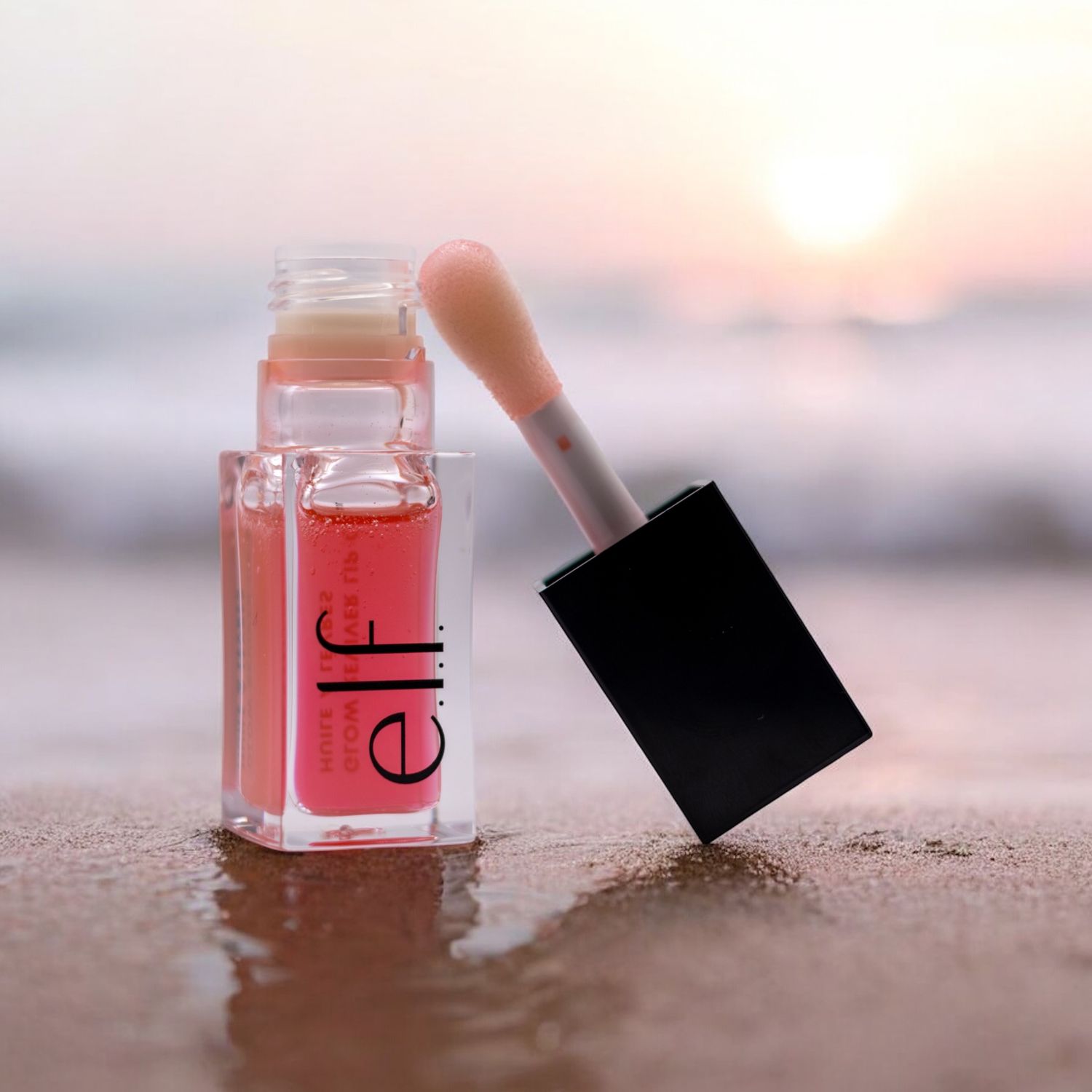 Pink beauty product jars photographed at sunset on sandy beach.