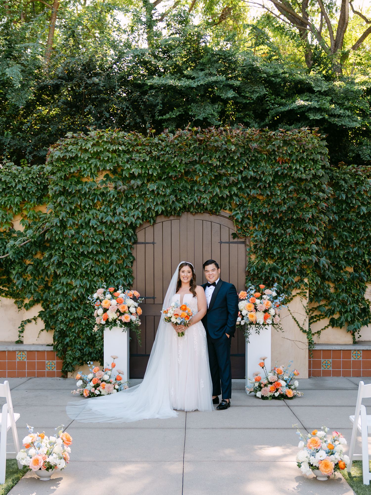 Bride and groom pose together on golf course with dramatic flowing veil.