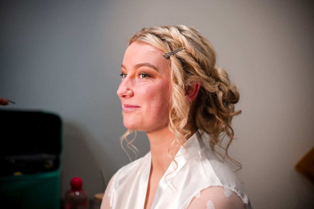 A bride with elegant curled hair and white lace dress prepares for her wedding day in a series of candid moments.