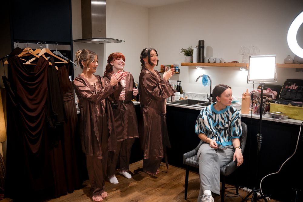 Behind the scenes photo of a group in matching brown robes preparing for a photoshoot in a studio setting.