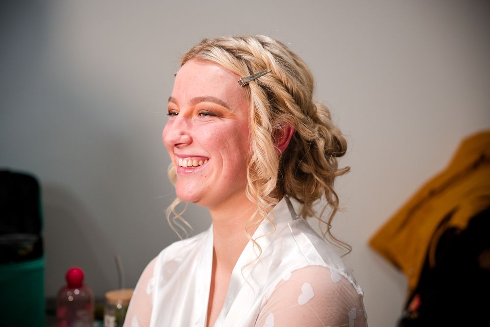 A person getting ready for a wedding ceremony with hair and makeup being styled in a bridal preparation room.