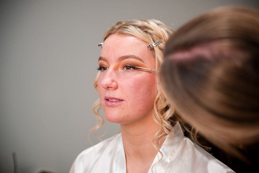 A series of candid getting-ready moments captured in soft lighting with a white robe and natural makeup.