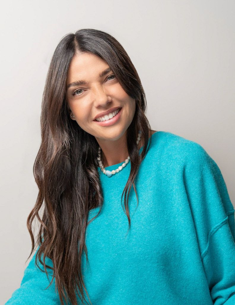 Retrato de mujer sonriendo frente a fondo neutro con iluminación suave