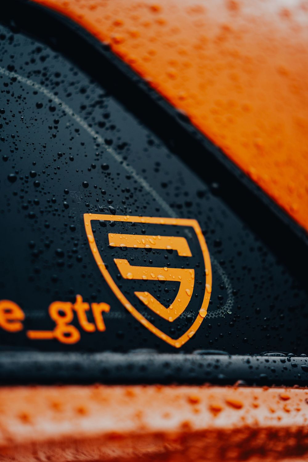 Abstract orange and black background with partial logo elements visible in high contrast detail.