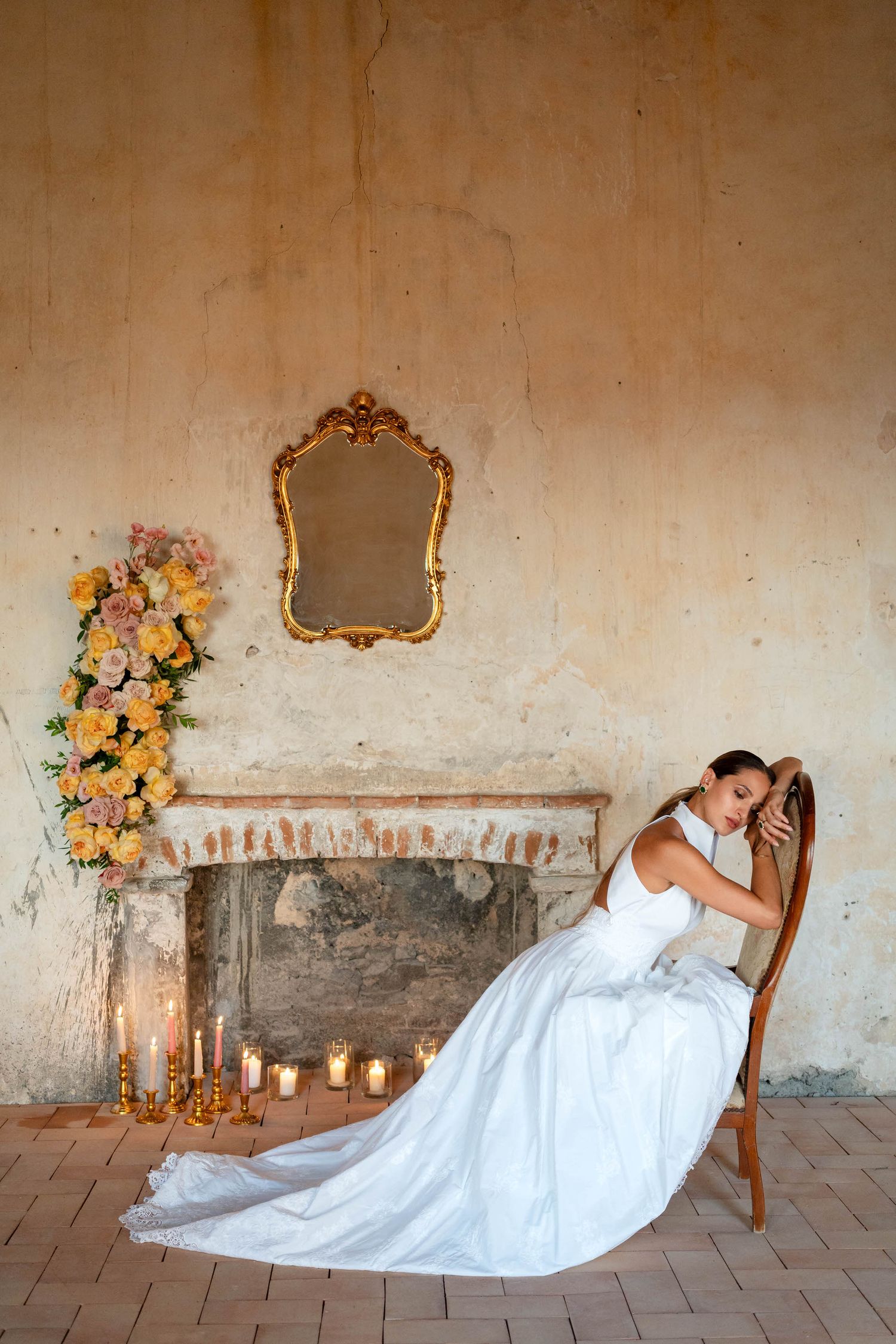 A bride in a flowing white wedding gown stands gracefully in a sunlit room with black and white checkered floors.