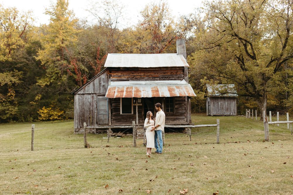 Rustic wooden barn with metal roof sits in autumn field surrounded by golden trees and natural landscape.