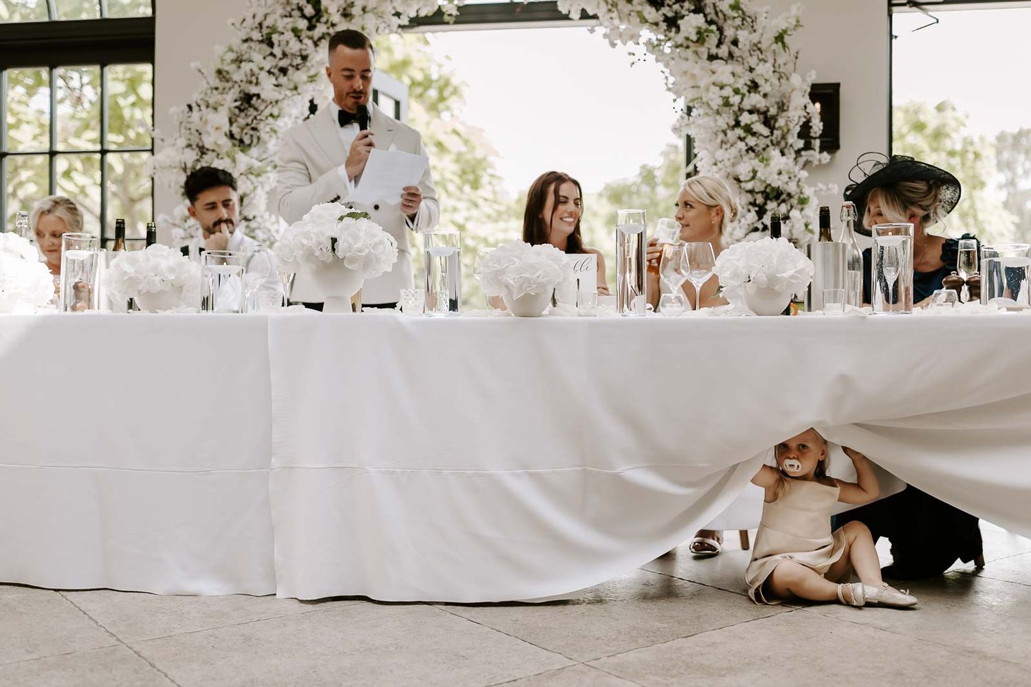 A series of wedding photos showing candid moments between the couple and guests at a reception with white decor.