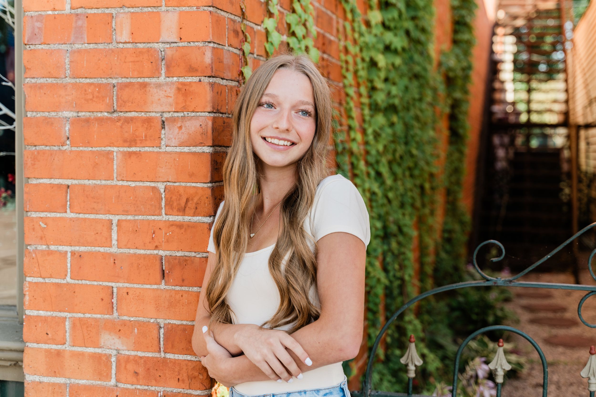 Four portrait photos against a rustic brick wall with climbing ivy create an artistic outdoor photography series.