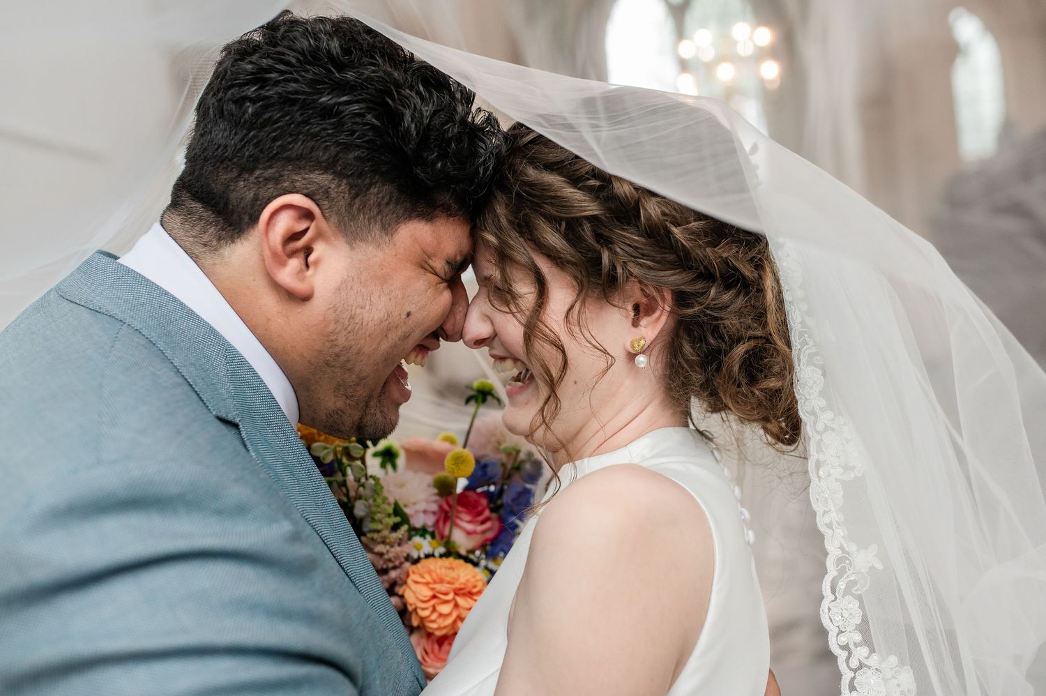 Fotoshoot van bruid en bruidegom lachend onder sluier, gefotografeerd door christelijke trouwfotograaf uit Blaricum