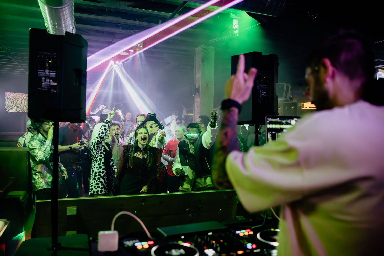 DJ performs at a wedding reception with colorful green lighting and dancing crowd.