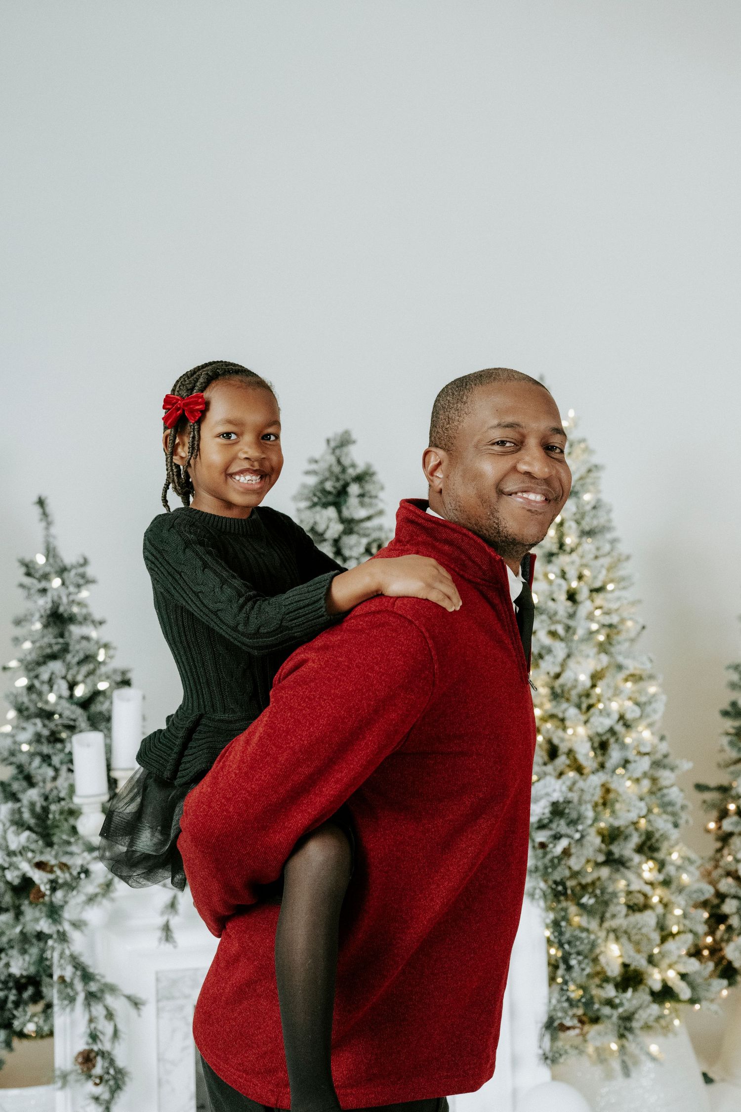 Two people share a warm embrace in front of a decorated Christmas tree in a cozy indoor setting.