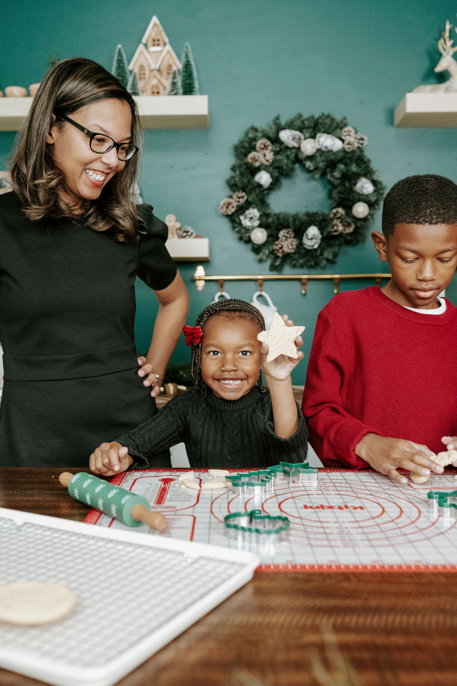 Children sit at a table working on holiday crafts and activities with festive decorations in the background.
