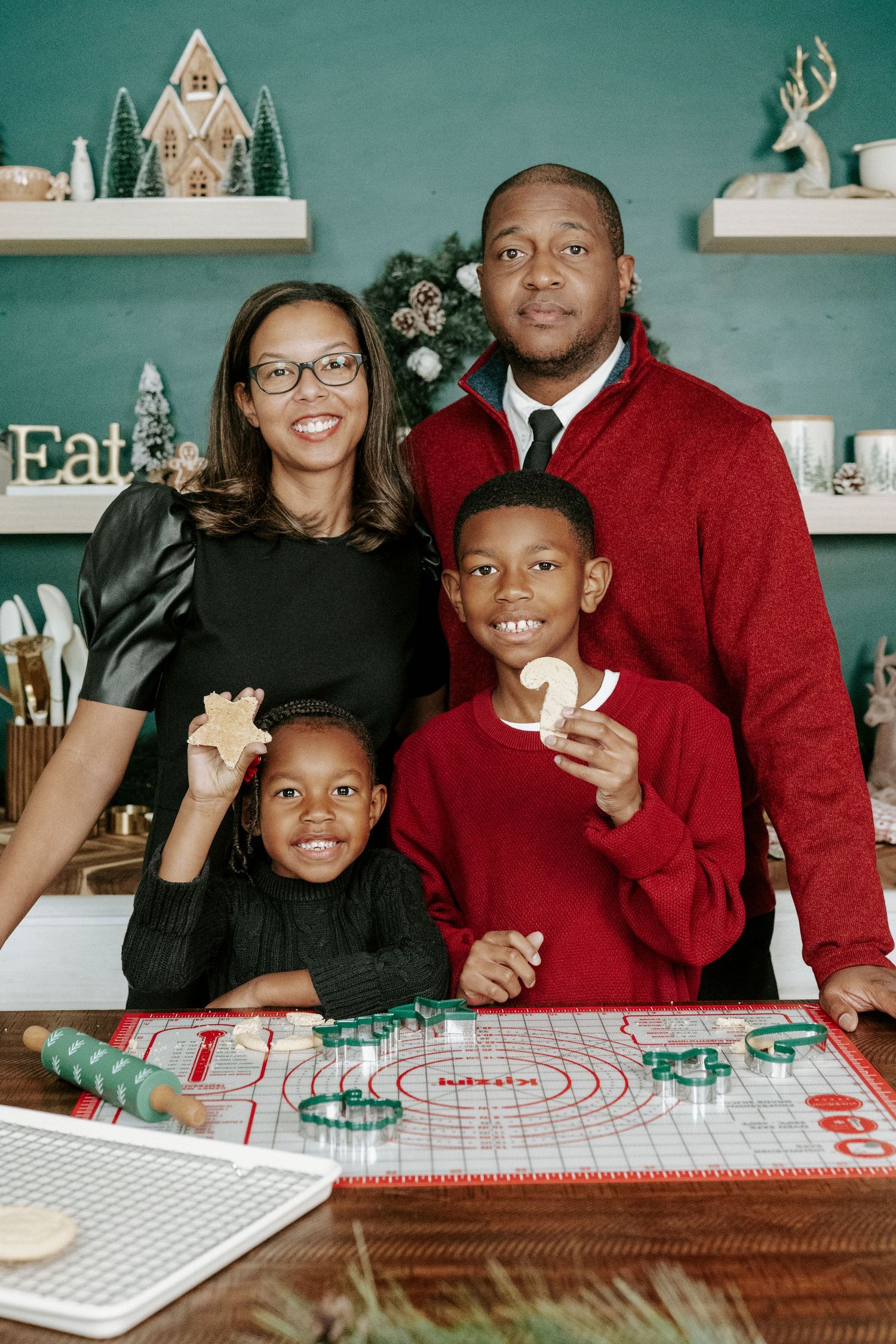 A family enjoys baking together in their kitchen during the holidays, gathered around a red and white checkered tablecloth.