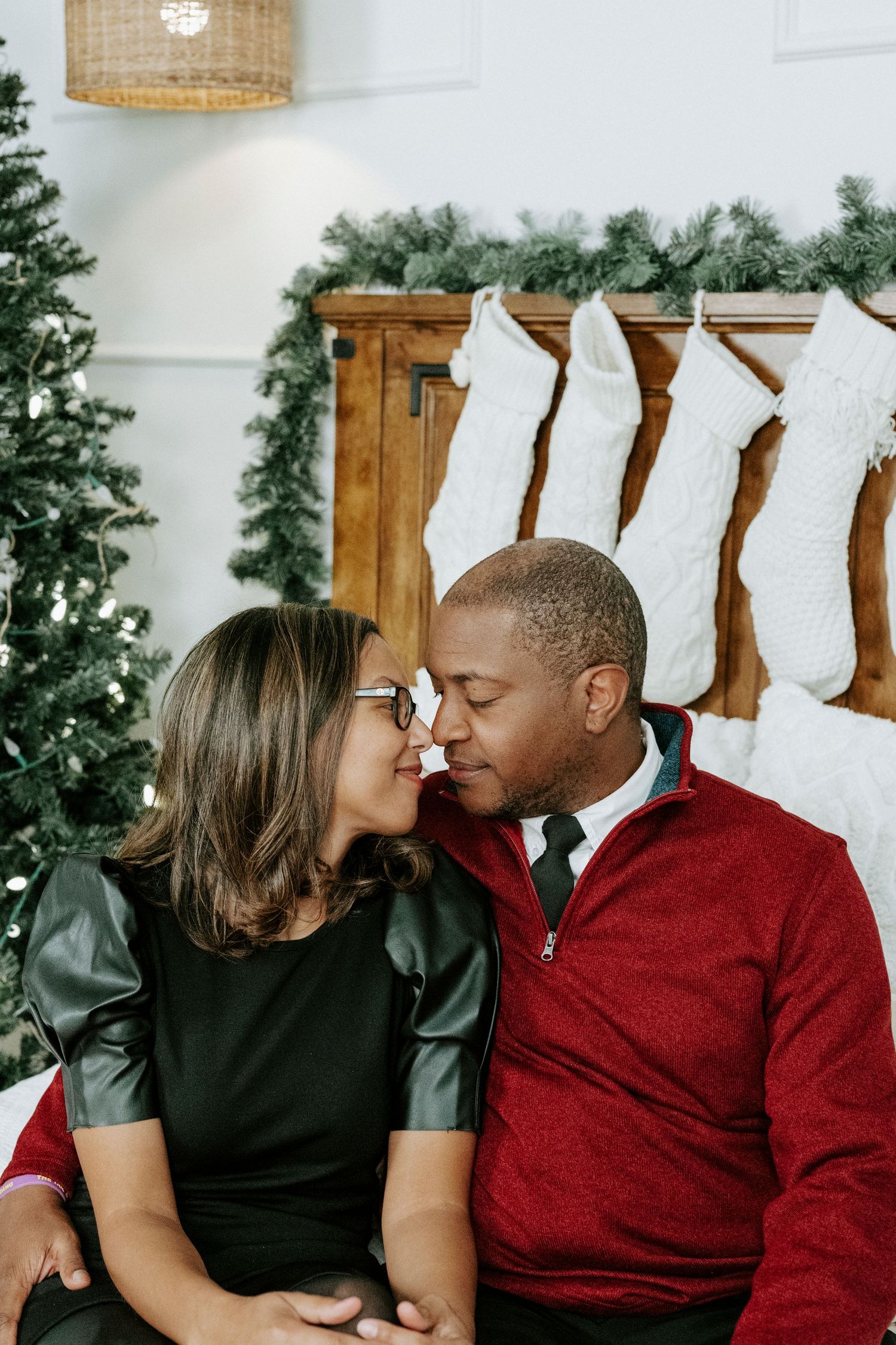A romantic couple shares intimate kisses in a series of photos with white stockings and holiday decor in the background.