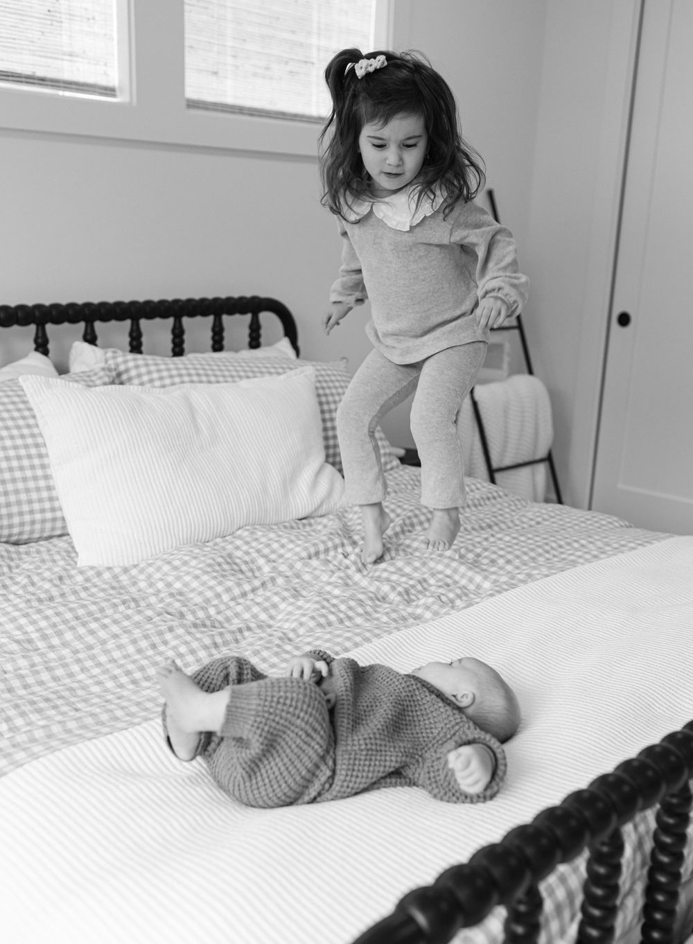 Black and white photos showing a child playing with toys on a checkered bedspread.