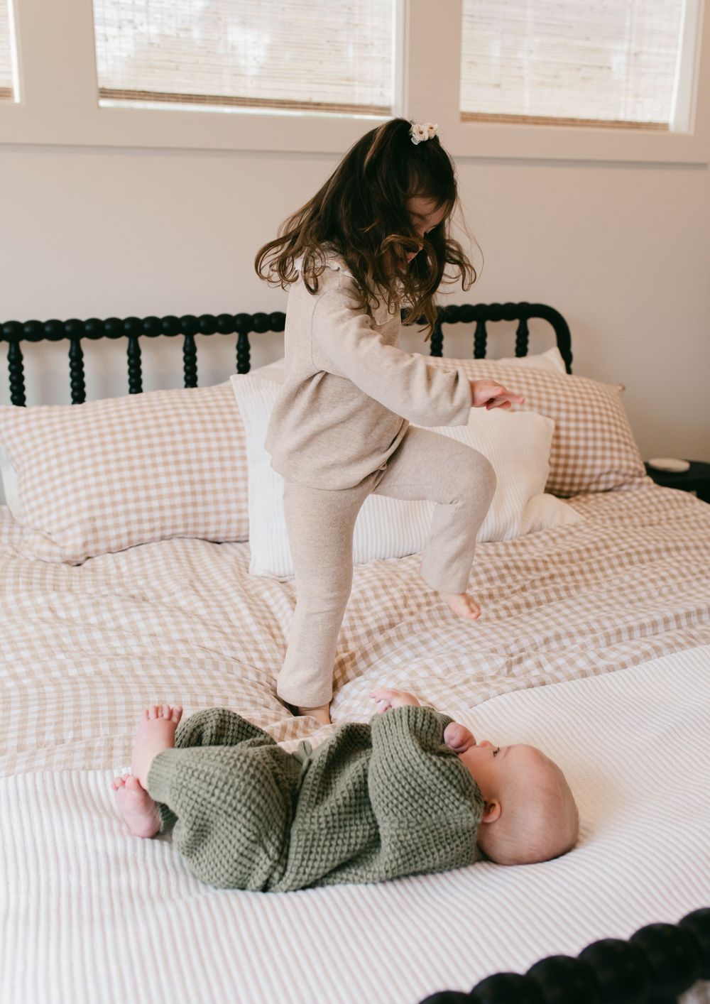 A sequence of playful moments on a white bed with gingham pattern bedding.