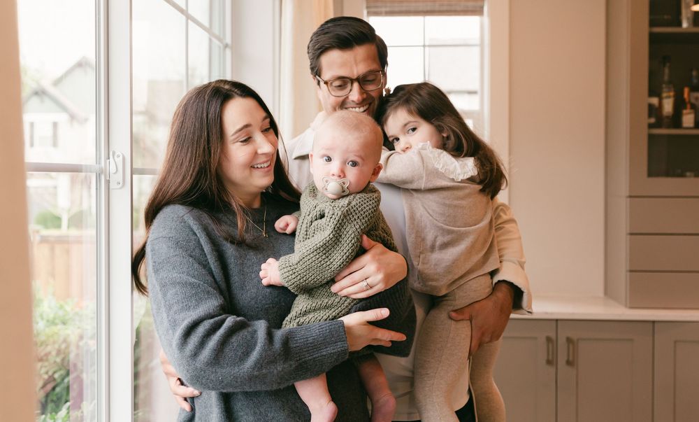 A family enjoys tender moments together in a bright, modern kitchen setting.