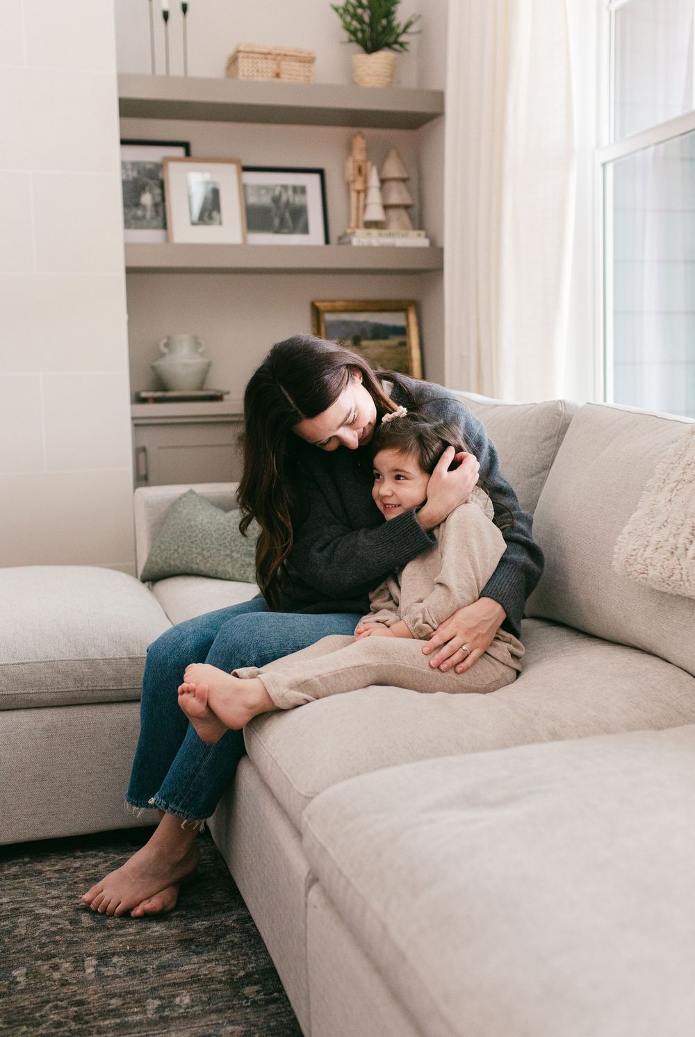 Candid lifestyle shots of family bonding on a comfortable gray couch in a bright living room.
