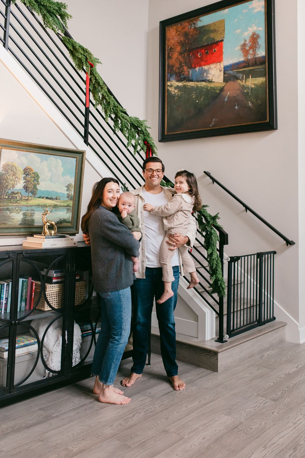 A family enjoys playful moments together in a modern home with artwork and a staircase in the background.