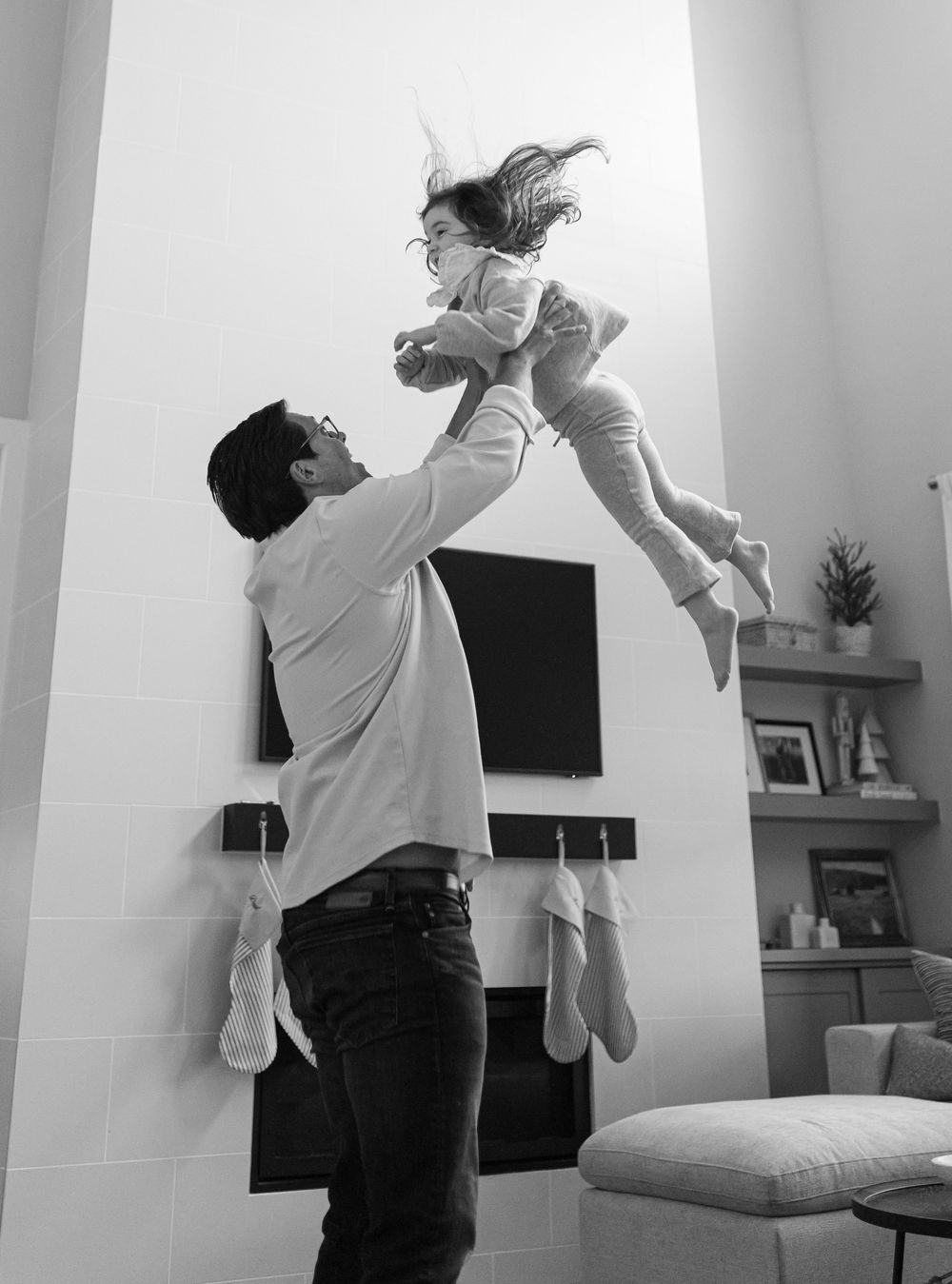 Black and white sequence showing playful moments between family members in a modern living room.