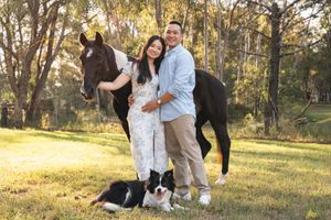 Couple enjoys a romantic sunset photoshoot in a wooded park setting with golden light filtering through trees wit ha horse and dog in Sydney