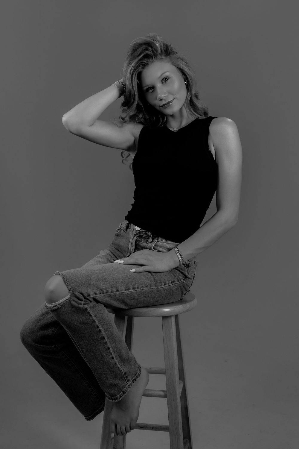 Artistic black and white portrait series showing dynamic poses on a simple stool against dark background.