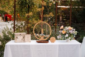 Elegant outdoor wedding reception setup with wooden tables, floral arrangements, and rustic decor in a garden setting.