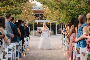Wedding guests seated in white chairs on an outdoor patio during an autumn ceremony.