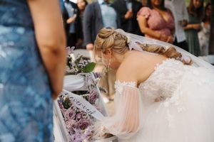 A couple embraces during a romantic outdoor wedding ceremony with purple floral bouquets and decor.