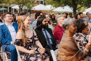 Wedding guests share joyful laughter during an outdoor reception celebration on a sunny afternoon.