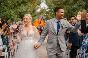 Wedding party celebrates outdoors with joyful dancing and laughter during a summer garden reception.